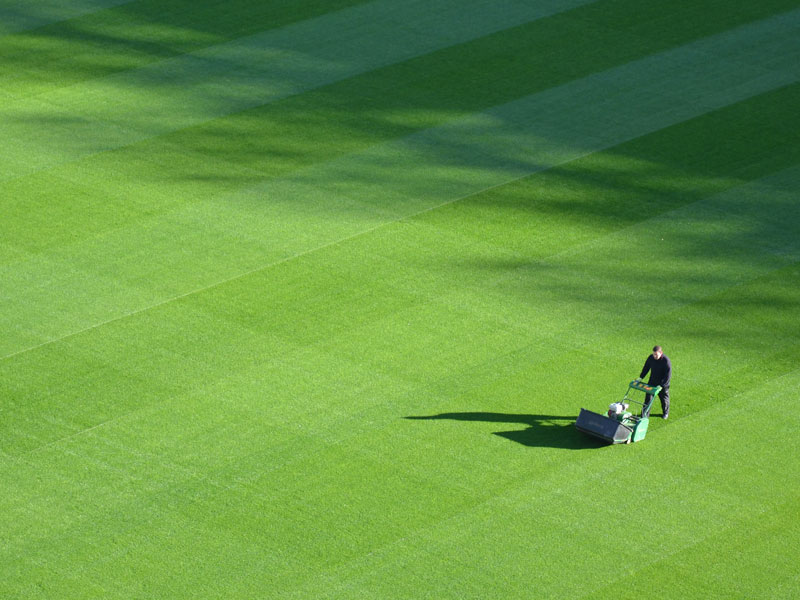 Person mowing the lawn of a ball park