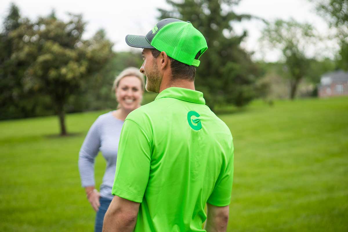 A homeowner talking with a green group employee on a lawn