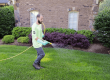 Green group employee spraying liquid aerator onto lawn.
